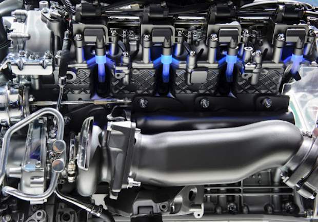 Close-up view of a modern car engine showing various metallic components, cylinders, and blue ignition light effects, highlighting technical details and complex machinery.